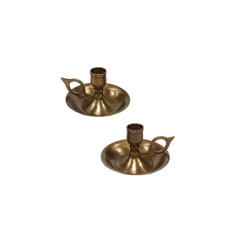 Two antique brass chambersticks with a brown patina, featuring a round base and a single candle holder, isolated on a white background.